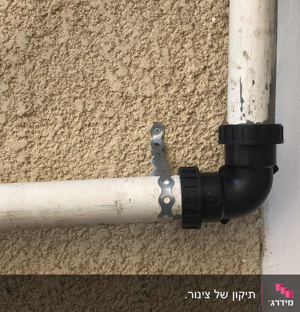 צינור פלסטיק עם מחבר זוויתי על קיר